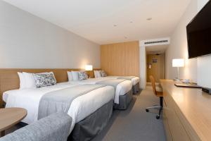 a hotel room with three beds and a flat screen tv at Keio Plaza Hotel Tokyo in Tokyo