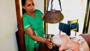 a woman getting her hair cut in a salon at Rico Shadow Guest House & Restaurant in Waikkal