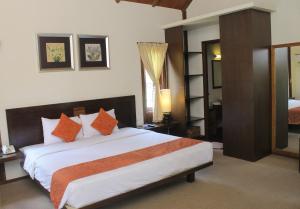 a bedroom with a large bed with orange pillows at Gardenia Resort and Spa in Pontianak