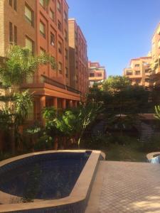 a pool in a courtyard in a city with buildings at Appartement Maria in Marrakech