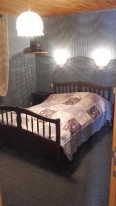 Un dormitorio con una cama de madera con dos luces. en La Grande Lauze, en Champcella