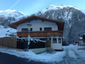 a house in the snow with mountains in the background at Appartement Gisela in Sölden