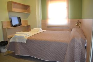 1 dormitorio con 1 cama, TV y ventana en The Factory Residence Hall, en Segovia