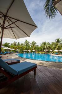 a chair and an umbrella next to a swimming pool at Blue Ocean Resort in Mui Ne