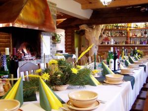una mesa larga con platos, tazones y flores. en Wellness Penzion u Michala, en Zuberec