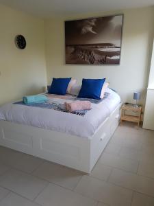 ein weißes Bett mit blauen Kissen in einem Zimmer in der Unterkunft "meidoornhofje" in Nieuwpoort