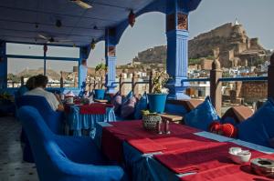 a restaurant with blue tables and a view of the acropolis at Raj Mandir Boutique Home Stay in Jodhpur