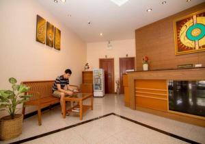 a man sitting on a bench in a living room at Prachuap Place Hotel in Prachuap Khiri Khan