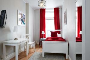 a bedroom with red curtains and a bed and a desk at Hotel Hornsgatan in Stockholm