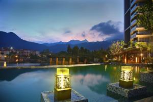 a hotel swimming pool with mountains in the background at Shenzhen Dameisha Kingkey Palace Hotel in Shenzhen