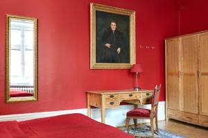 a red bedroom with a desk and a painting on the wall at Hotel Hornsgatan in Stockholm
