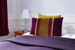 a bed with a purple blanket and a colorful pillow at Hotel Hornsgatan in Stockholm
