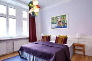 a bedroom with a bed with purple sheets and windows at Hotel Hornsgatan in Stockholm