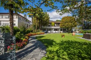 un jardin en face d'une maison avec une allée. dans l'établissement Hotel Ascovilla Charming Hideway, à Ascona