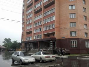 トゥーラにあるInndays on Pionerskaya 1-2の雨の中の建物の前に停車した車2台
