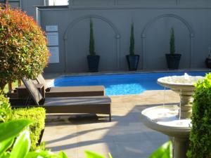 een zwembad in een tuin met 2 ligstoelen bij Gallery Apartments in Warrnambool