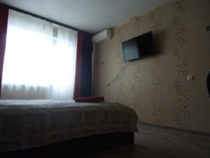 - une chambre avec un lit et une télévision murale dans l'établissement Apartments on Gagarina 9, à Volgodonsk