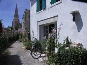 uma bicicleta estacionada fora de um edifício branco com flores em Maison Porcelaine em La Couarde-sur-Mer