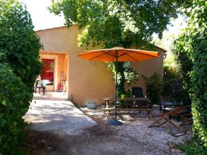 an orange umbrella and a table and a bench at Le Relais du Gapeau in Solliès-Toucas