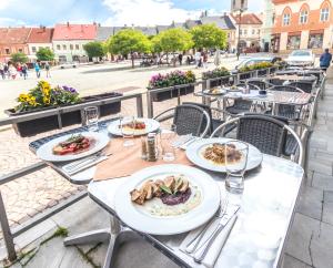 a table topped with plates of food on top of a patio at Hotel Mědínek Old Town in Kutná Hora