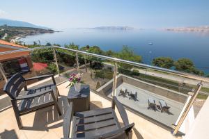 a balcony with two chairs and a view of the water at Villa Karamba in Senj