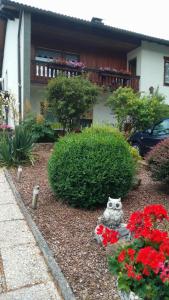 a garden with flowers and an owl statue in front of a house at Haus Waldesruh, 3 Ferienwohnungen in Hemfurth-Edersee