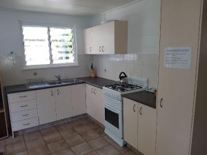 a kitchen with white cabinets and a stove and a window at Apurla Island Retreat in K'gari Island (Fraser Island)