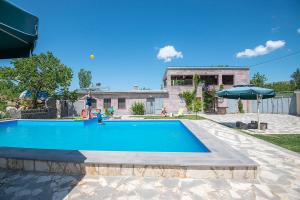 a swimming pool with an umbrella and a house at Camping 3 Gs in Goghtʼ