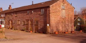 an old brick building with potted plants in front of it at The Shippon Barn - A delightful haven for families in Wirral