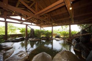 Kurasako Onsen Sakura في ميناميوغوني: بركة كبيرة فيها صخور وسقف خشبي