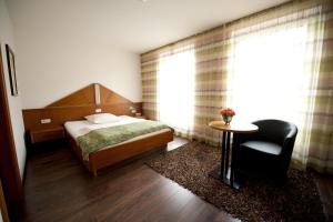 Un dormitorio con una cama, una mesa y una silla. en Classic Hotel Kaarst, en Kaarst