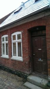 - un bâtiment en briques rouges avec une porte et deux fenêtres dans l'établissement Peder Dovns Slippe, à Ribe