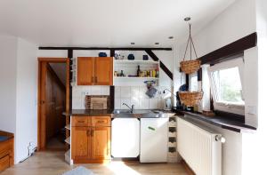 cocina con armarios de madera y nevera blanca en Morgensonne en Hiddensee