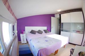 una camera da letto con pareti viola e un letto bianco di Leni a Fažana