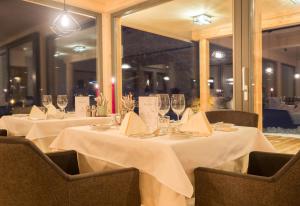 un comedor con 2 mesas con manteles blancos y copas de vino en Das Leonhard - Naturparkhotel am Weissensee, en Weissensee