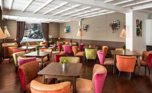 a restaurant with tables and chairs and pink chairs at Hotel Ormelune in Val-d'Isère