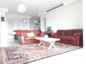 uma sala de estar com dois sofás de couro castanho e uma mesa em Shave Tsion Apartment in the center Ashdod em Ashdod