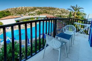 a balcony with chairs and a view of a pool at Hylatio Tourist Village in Pissouri