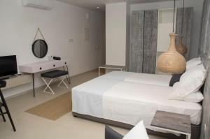 a bedroom with a bed and a desk and a television at Hylatio Tourist Village in Pissouri