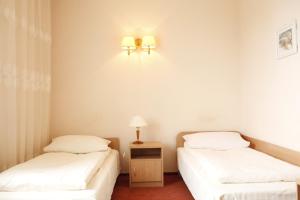 two beds in a room with two lamps on the wall at Iskra in Radom