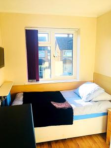 a bedroom with a bed with a window and a desk at Heather's Lodge in Cheshunt