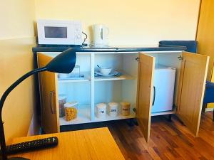 a cabinet with a microwave and a desk with a lamp at Heather's Lodge in Cheshunt