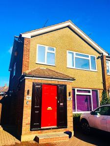 a brick house with a red door and a car at Heather's Lodge in Cheshunt