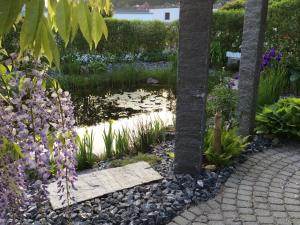 a garden with a pond and trees and flowers at BnB Villa Levanta in Péry