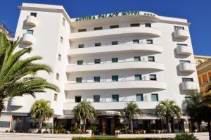 un grande edificio bianco con palme di fronte di Astura Palace Hotel a Nettuno