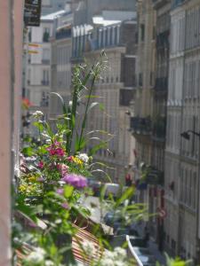 einen Blick auf die Stadt aus einem Fenster mit Blumen in der Unterkunft Les Toits de Paris in Paris