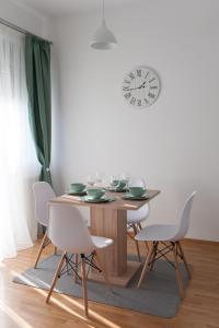 a dining room table with chairs and a clock on the wall at Apartment Ada in Belgrade