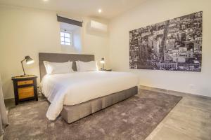 a bedroom with a large bed and a painting on the wall at Paço do Bispo Boutique House in Sintra +66 photos
