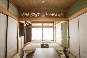 una camera con letto, tavolo e sedie di Guest House DOUGO-YADO a Matsuyama
