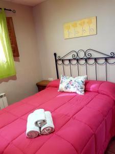 Una cama rosa con dos toallas y zapatos. en Camping Ruta del Purche, en Monachil